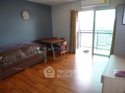 Spacious living room with balcony in modern apartment, featuring wooden flooring and stylish furniture.