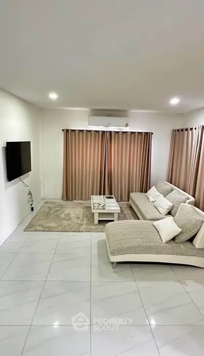 Spacious modern living room with elegant sofa and wall-mounted TV, perfect for relaxation and entertainment.