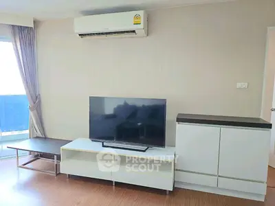 Modern living room with sleek TV stand and air conditioning, featuring natural light and minimalist decor.