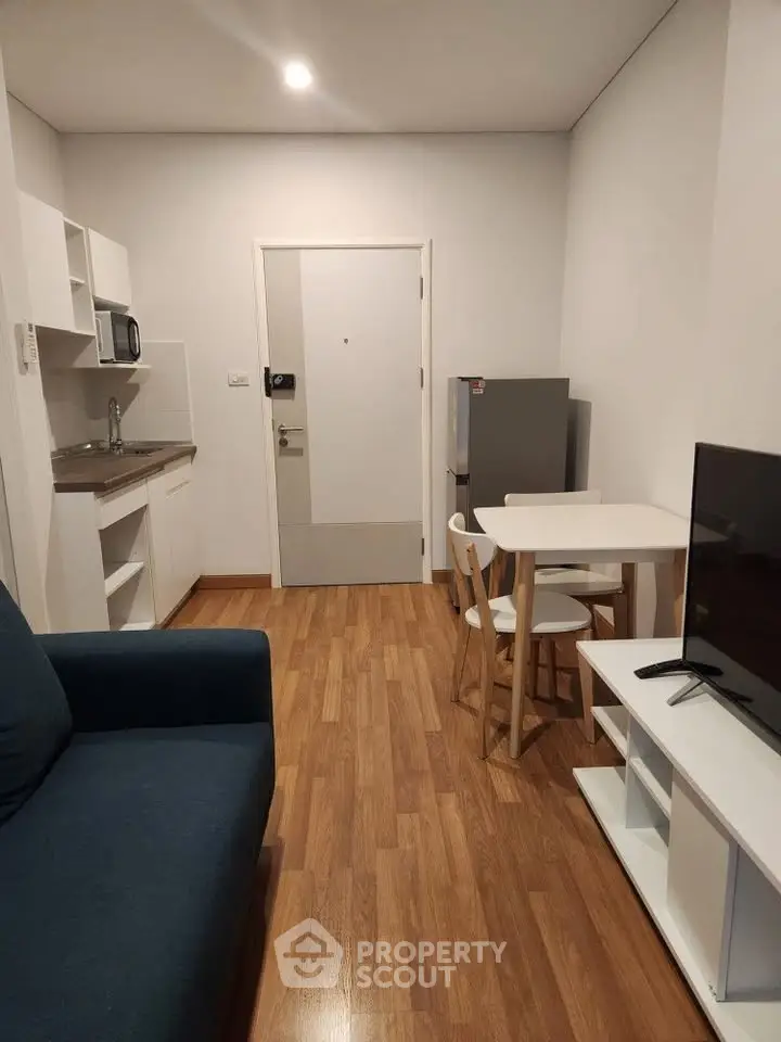 Cozy modern living room with kitchenette, wooden flooring, and compact dining area in a stylish apartment.