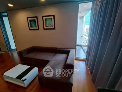 Cozy living room with modern sofa and coffee table, featuring wooden flooring and balcony access.