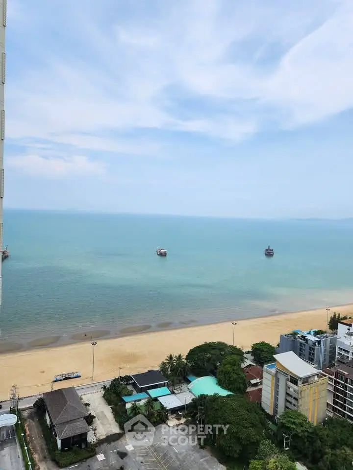 Stunning beachfront view from high-rise apartment overlooking serene ocean and sandy beach.
