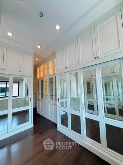 Luxurious walk-in closet with elegant cabinetry and mirrored doors in a modern home.