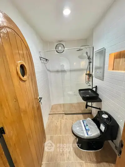 Modern bathroom with wooden door and sleek black fixtures