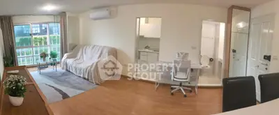 Spacious open-plan living room with modern kitchen and cozy study area, featuring natural light and stylish decor.
