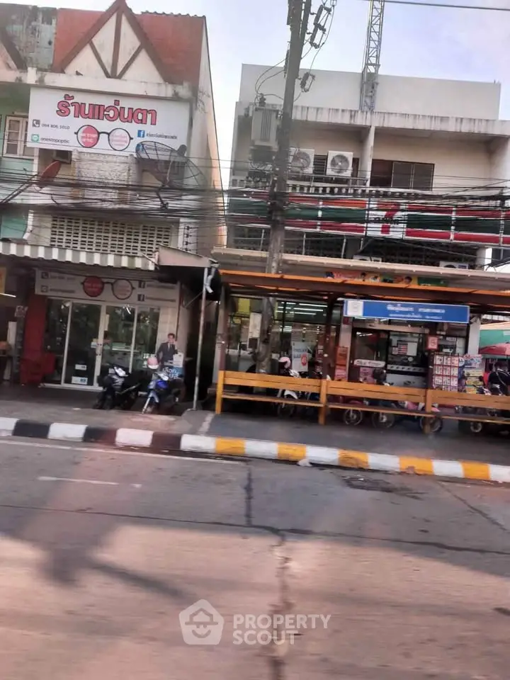 Street view of commercial buildings with shops and motorbikes in front, showcasing urban retail space.