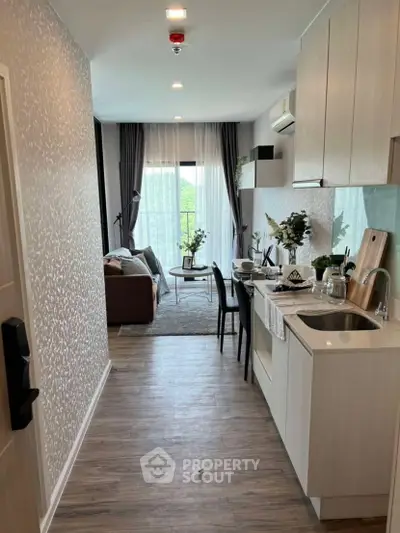Modern open-layout apartment with stylish kitchen and cozy living area, featuring large windows and elegant decor.