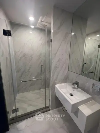 Modern bathroom with glass shower and sleek sink in luxury apartment