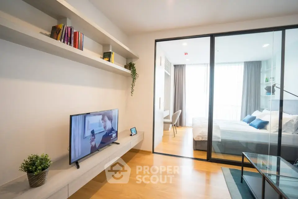 Modern apartment with open living room and bedroom, featuring sleek design and natural light.