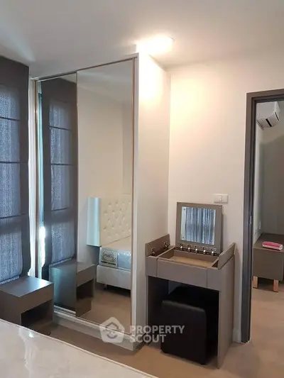 Modern bedroom with mirrored wardrobe and stylish vanity in a cozy apartment.