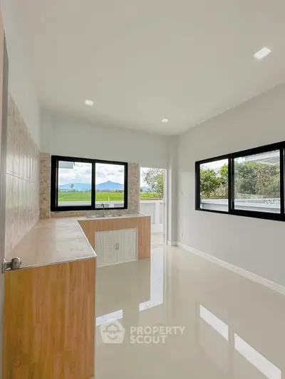 Modern kitchen with large windows and scenic view, featuring sleek countertops and ample natural light.