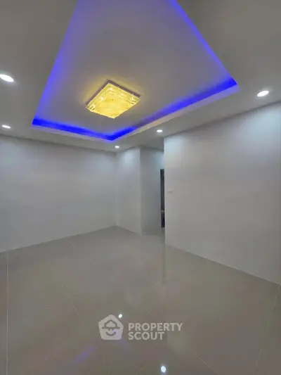 Modern living room with sleek tile flooring and ambient LED ceiling lights.