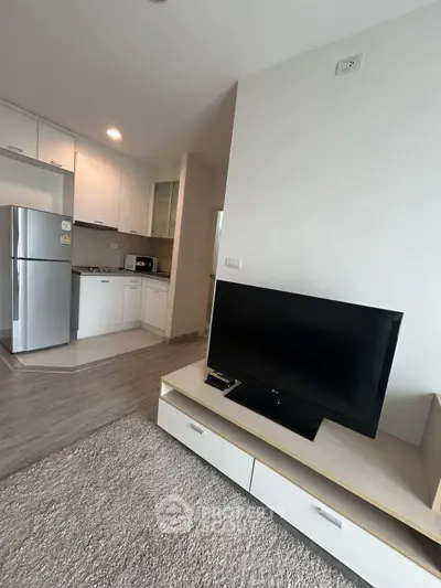 Modern living room with sleek kitchen and large TV, featuring contemporary design and open layout.