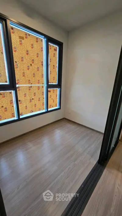 Bright empty room with large windows and wooden flooring, perfect for customization.