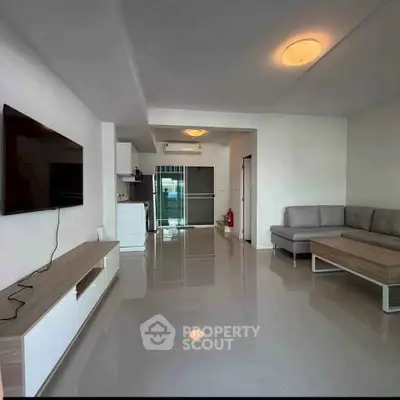 Spacious modern living room with sleek furniture and open kitchen layout in a contemporary apartment.
