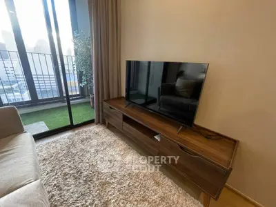 Modern living room with TV unit and balcony view in urban apartment.