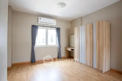 Spacious bedroom with wooden flooring and modern wardrobe