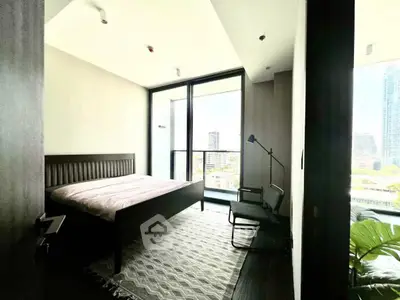 Modern bedroom with large windows offering city views and stylish furnishings.