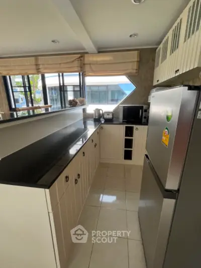 Modern kitchen with sleek black countertops and stainless steel appliances in a bright open layout.