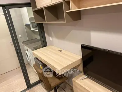 Modern compact study area with built-in desk and TV, adjacent to a sleek kitchen with washing machine.