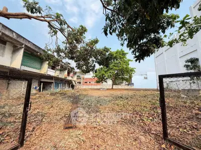 Spacious vacant lot with potential for development, surrounded by residential buildings and lush greenery.