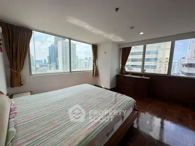 Spacious bedroom with panoramic city view and elegant wooden flooring.