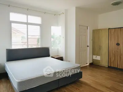 Spacious bedroom with large windows and wooden flooring in a modern home.