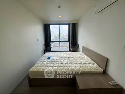 Spacious bedroom with large window offering city views, featuring a comfortable bed and modern furnishings.