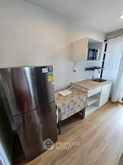 Modern compact kitchen with stainless steel fridge and microwave, perfect for urban living.