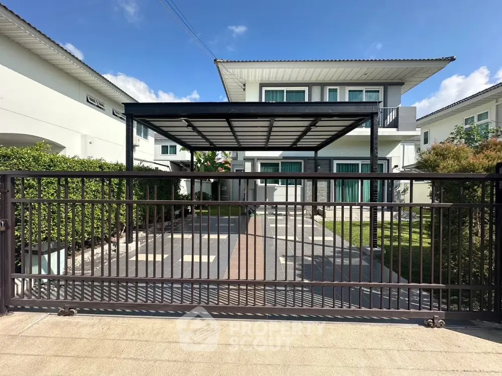 Modern two-story house with gated driveway and carport in sunny neighborhood.