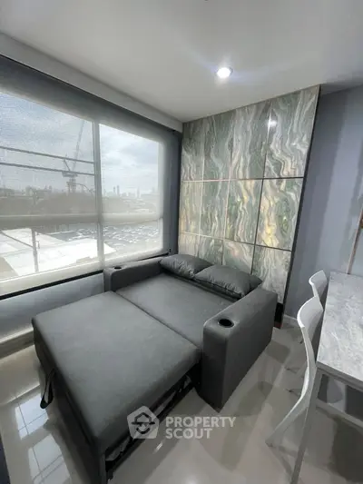 Modern studio apartment with stylish sofa bed and marble accent wall, offering city views.