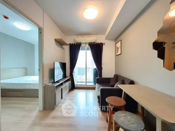 Modern living room with cozy sofa and TV, adjacent to a bright bedroom with balcony access.