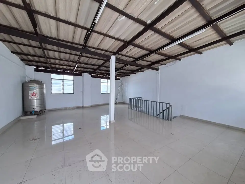 Spacious industrial-style room with metal roof and polished tile floor, ideal for storage or workshop.