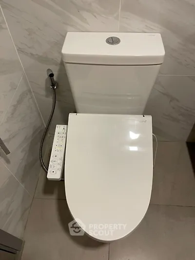 Modern bathroom with sleek toilet and bidet attachment in a contemporary setting.