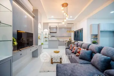 Luxurious modern living room with plush seating and elegant lighting, open to a stylish kitchen.