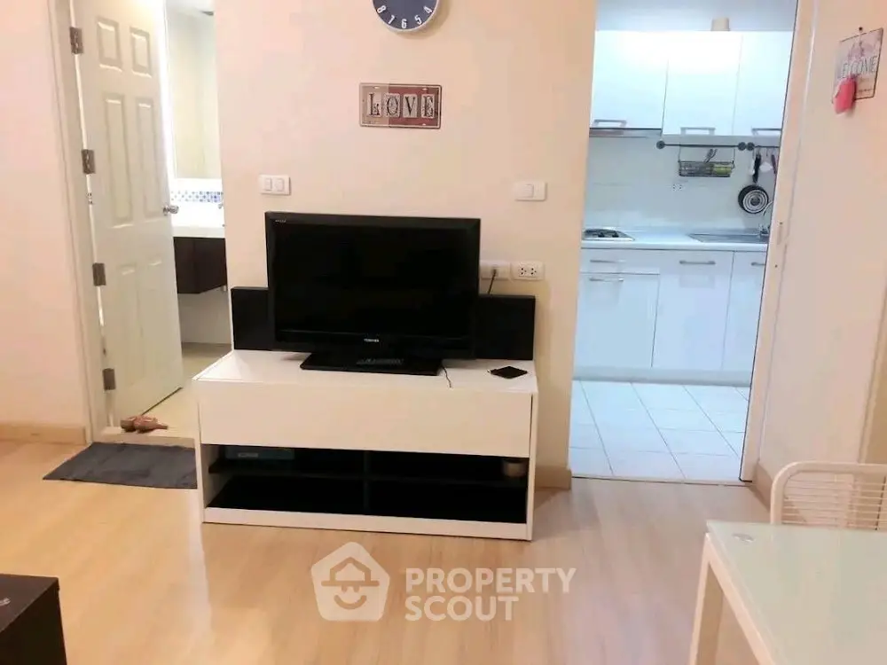 Cozy living room with TV and view into modern kitchen