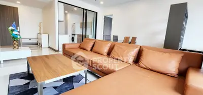 Spacious modern living room with leather sofa and open kitchen layout