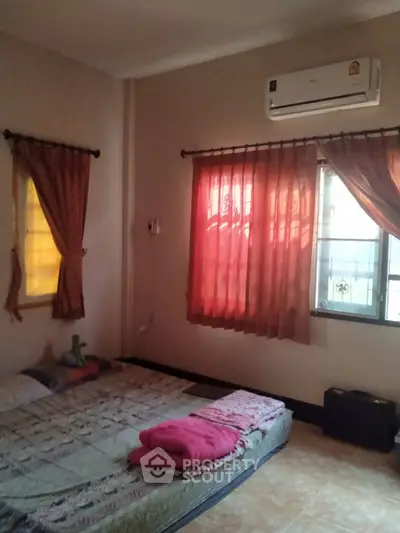 Cozy bedroom with air conditioning and natural light through curtained windows.