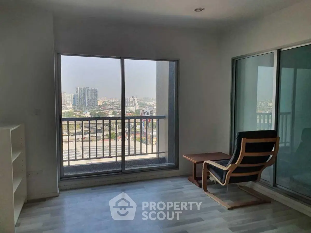 Bright living room with large window offering city view and minimalist furniture.