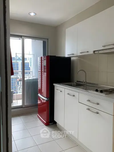 Modern kitchen with red fridge and balcony view in urban apartment