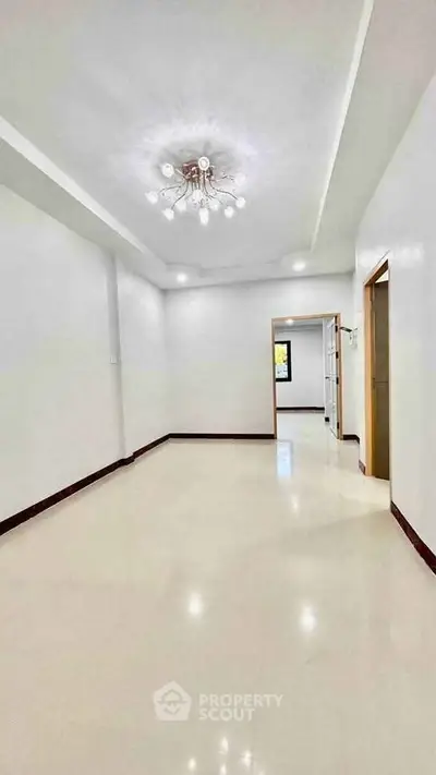 Spacious empty room with modern chandelier and polished floors