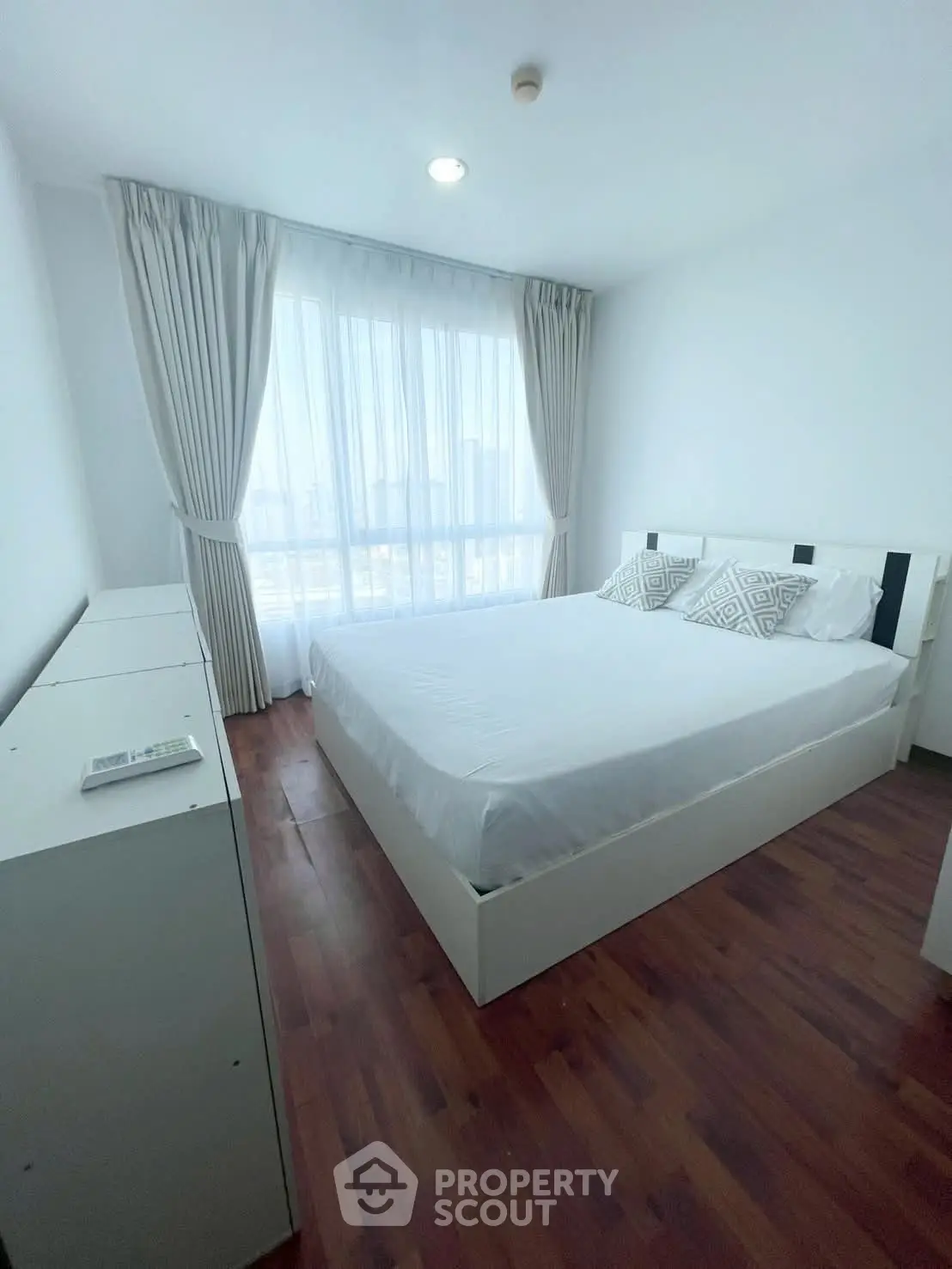 Bright and cozy bedroom with wooden flooring and large window view