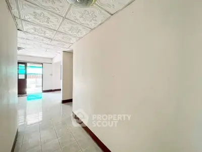 Spacious hallway with decorative ceiling tiles and bright natural light.