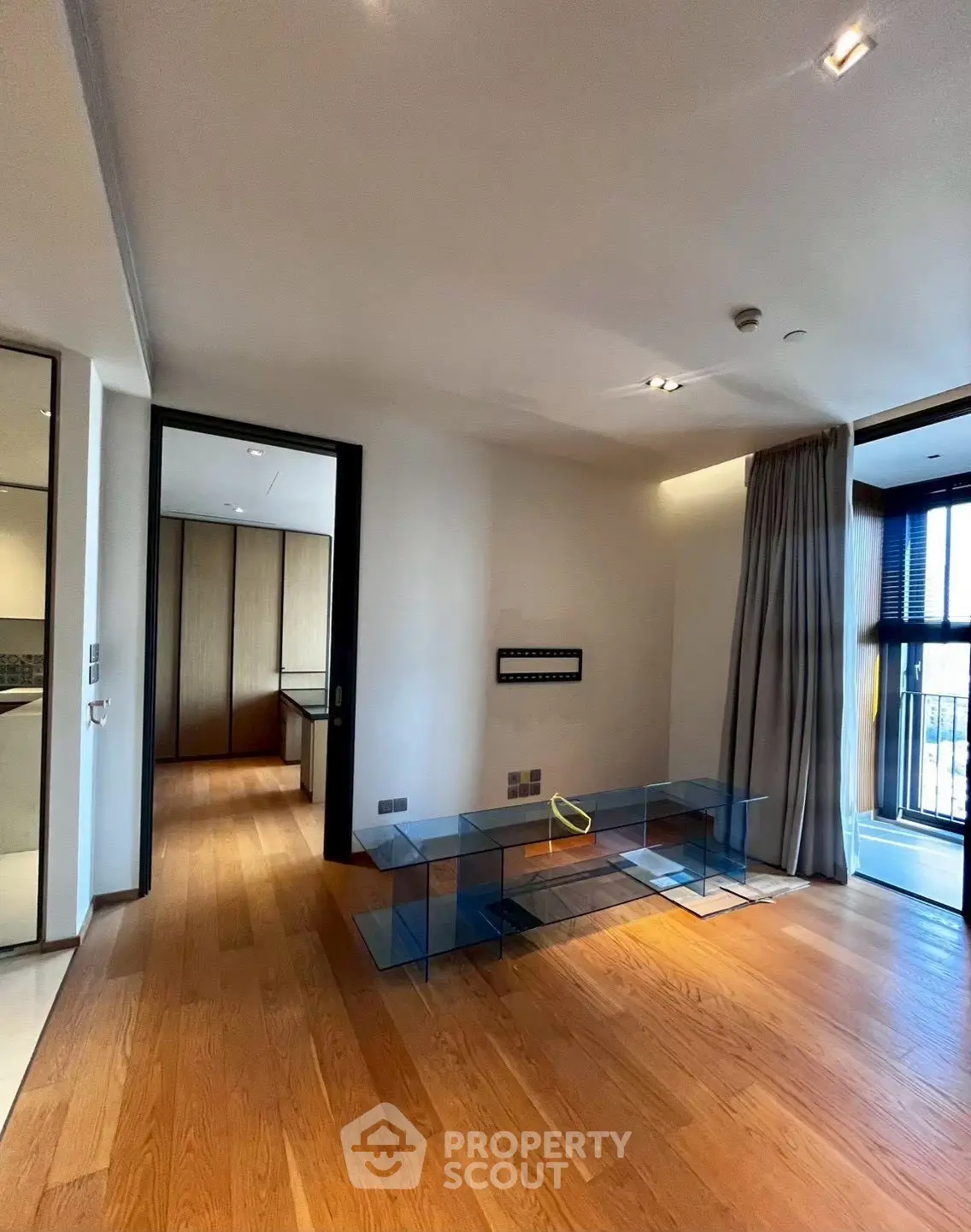 Spacious modern living room with wooden flooring and large windows for natural light.