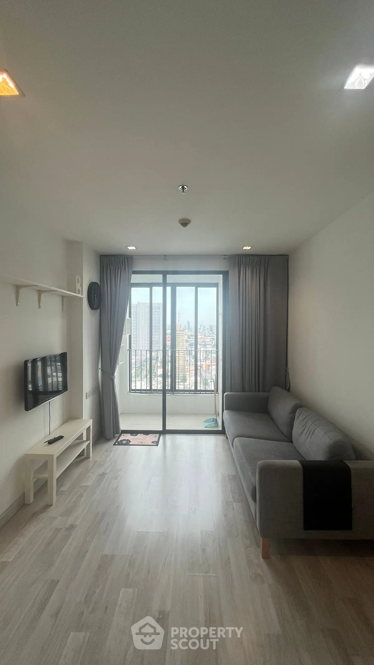 Spacious living room with modern decor and city view from large windows.