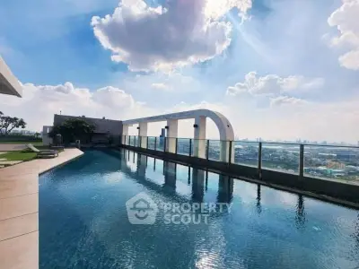 Stunning rooftop pool with panoramic city views under a bright blue sky.