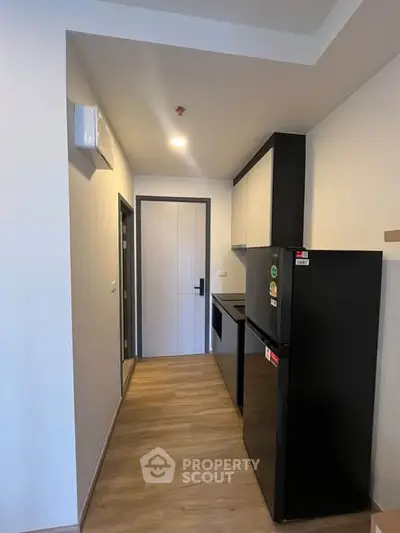 Modern compact kitchen with sleek black appliances and wooden flooring