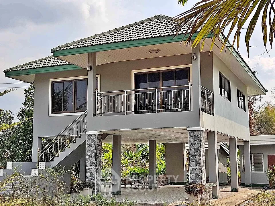 Elevated modern house with tiled roof and spacious balcony in lush setting