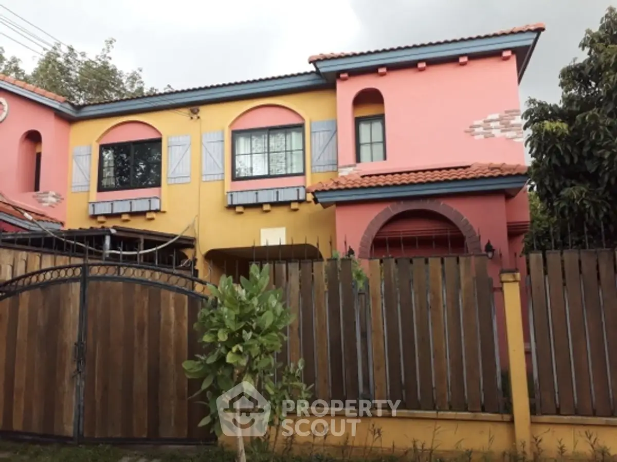 Charming colorful two-story house with unique architectural design and wooden fence.