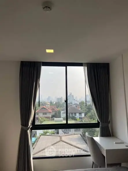 Bright room with large window offering a stunning city view, perfect for a home office setup.